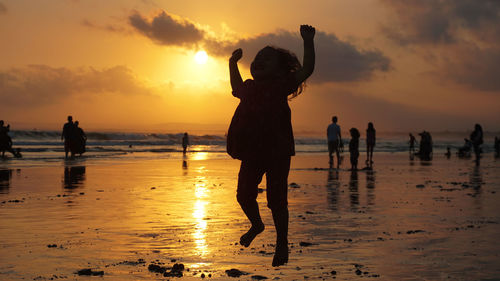 Silhouette people on beach against sky during sunset