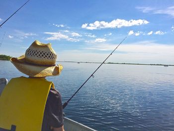 Rear view of man fishing while traveling in boat on sea