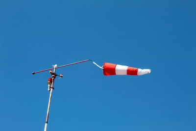 Low angle view of telephone pole against clear blue sky