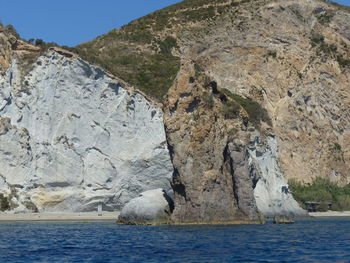 Scenic view of sea by mountain against sky