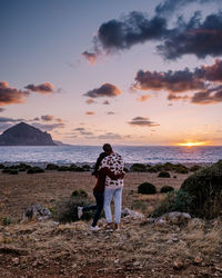 Woman standing on beach against sky during sunset