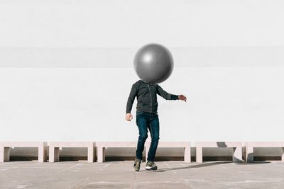 Man playing with ball against wall