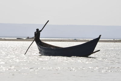 Man on boat in sea against sky