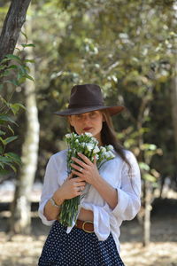 Young woman wearing hat standing against plants