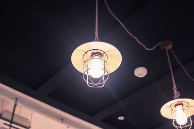 Low angle view of illuminated pendant light hanging from ceiling