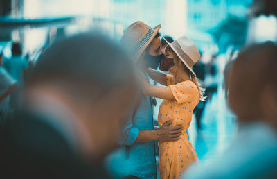 Side view of couple wearing mask kissing outdoors