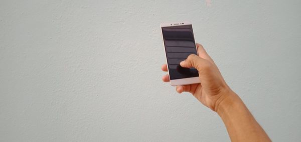 Midsection of person holding camera against wall