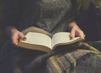 Midsection of woman reading book