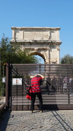 Rear view of man against built structure against clear sky