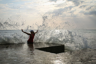 Wave splashing on woman at sea shore