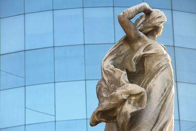 Statue at recoleta cemetery against modern building