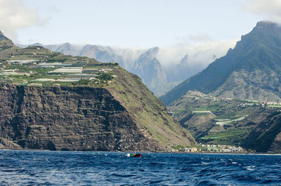 Scenic view of sea by mountains against sky