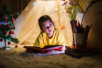 Portrait of girl sitting on table at home