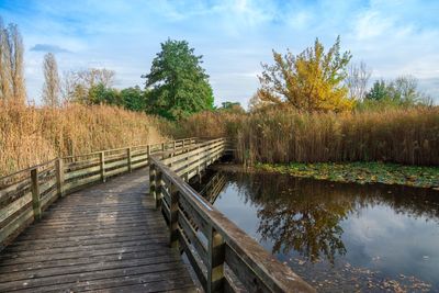 Footbridge over lake against sky