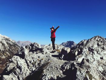 Man standing on rock against blue sky