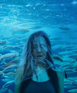 Mature woman covered in plastic against aquarium