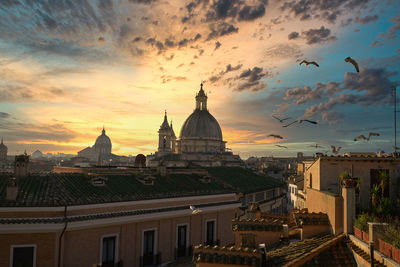 Buildings in city against sky during sunset