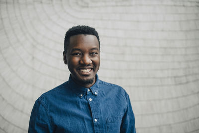 Portrait of smiling businessman against gray wall