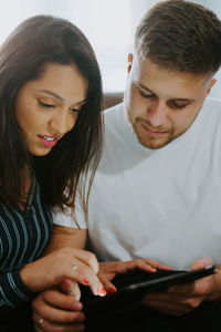 Couple browsing tablet computer while entertaining at weekend