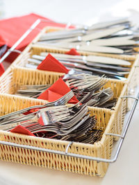 High angle view of forks and table knives in baskets on table