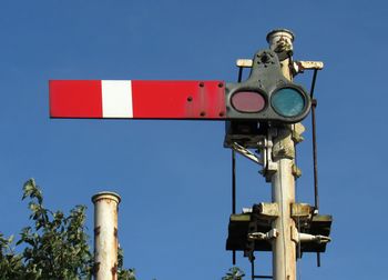 Low angle view of telephone pole against clear blue sky