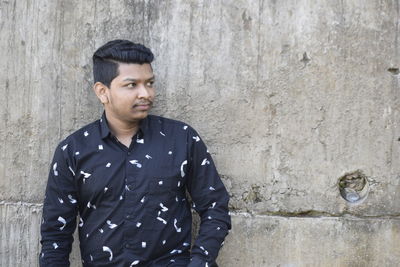 Portrait of young man standing against wall