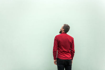 Rear view of man standing against red wall