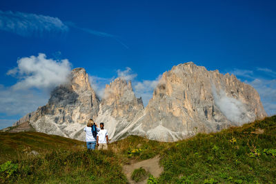 People hiking on mountain against blue sky