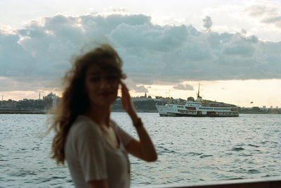 Woman standing by sea against sky