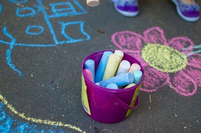 Close-up of container of colorful chalk near chalk drawing