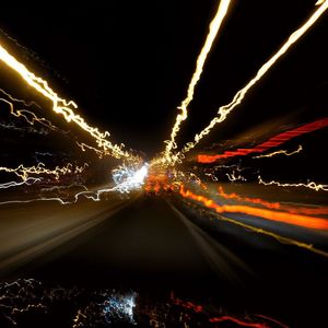 Light trails on road against sky at night