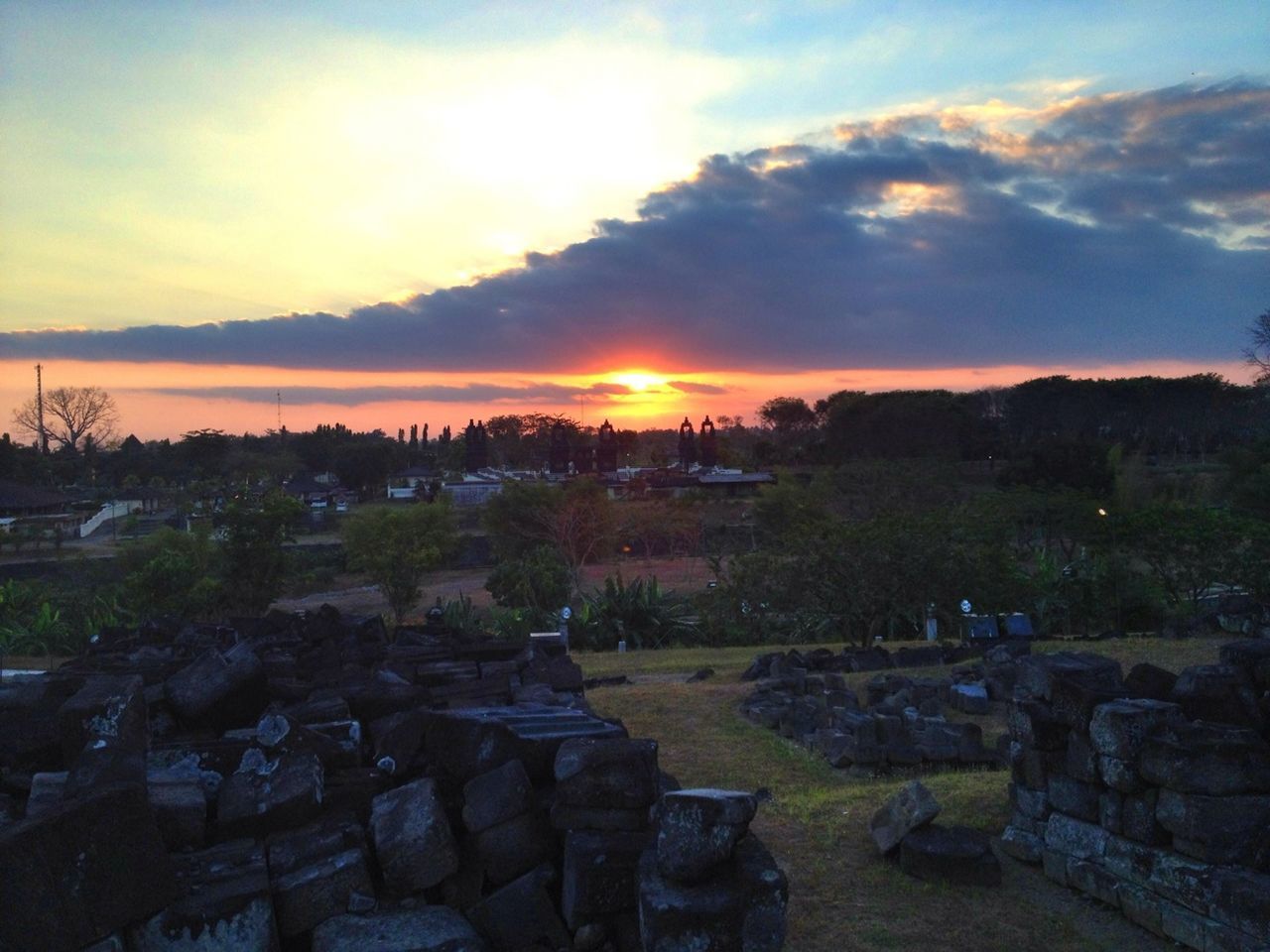 sunset, sky, cloud - sky, rock - object, sun, tranquility, scenics, landscape, tranquil scene, stone - object, sunlight, nature, travel destinations, orange color, tree, stone material, cloud, sunbeam, beauty in nature, built structure