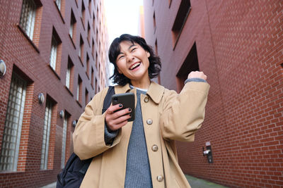 Young woman standing against building