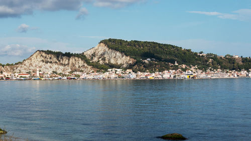 Scenic view of sea by townscape against sky