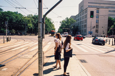 Rear view of people walking on street in city