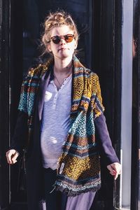 Young woman wearing sunglasses walking against building