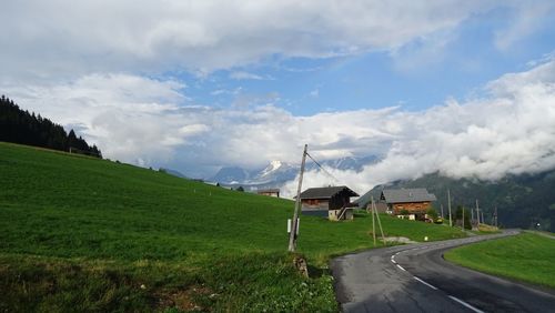 Road amidst field against sky