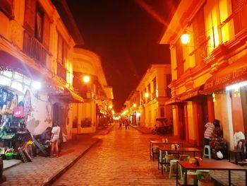 People on illuminated street at night