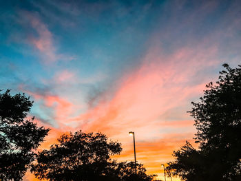 Low angle view of silhouette trees against dramatic sky