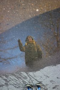 Boy reflecting in puddle during winter