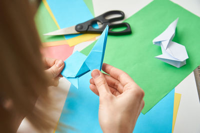 Origami lessons. woman make origami easter rabbit from color paper. diy concept