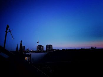 Silhouette of city against blue sky