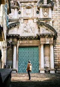Rear view full length of man standing outside historic building