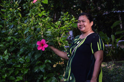 Portrait of young woman standing amidst plants