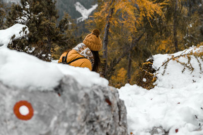 Rear view of young woman hiking on snowy path in mountains