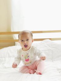 Portrait of cute baby girl lying on bed at home
