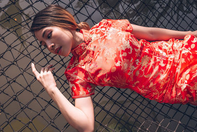 Portrait of woman holding chainlink fence