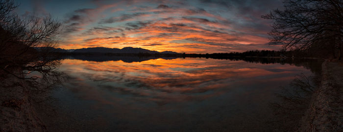 Scenic view of lake against dramatic sky during sunset