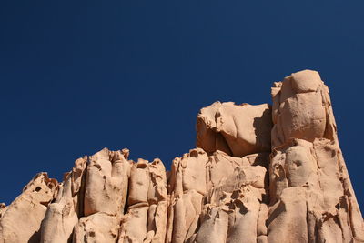 Low angle view of rocks against blue sky