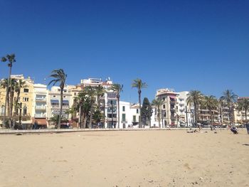 Residential buildings by beach against clear sky